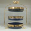 1781617069_WhatsApp_Image_2026-06-12_at_14.33.11-1.jpg Three-tier ceramic serving stand with a gold metal frame
